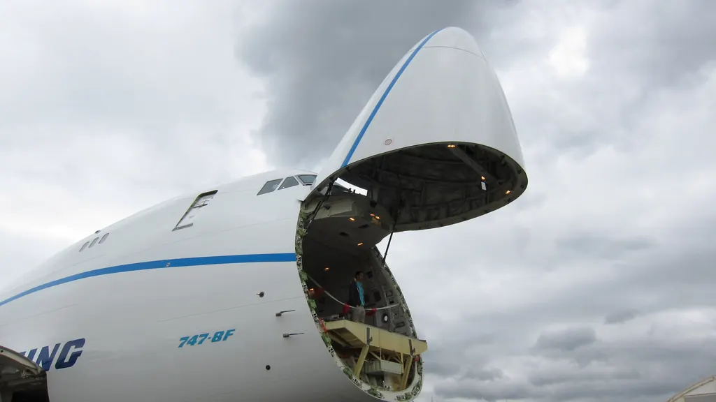 The hinged nose of a freighter aircraft raised clear of the fuselage, exposing the main-deck loading aperture and the roller floor inside.