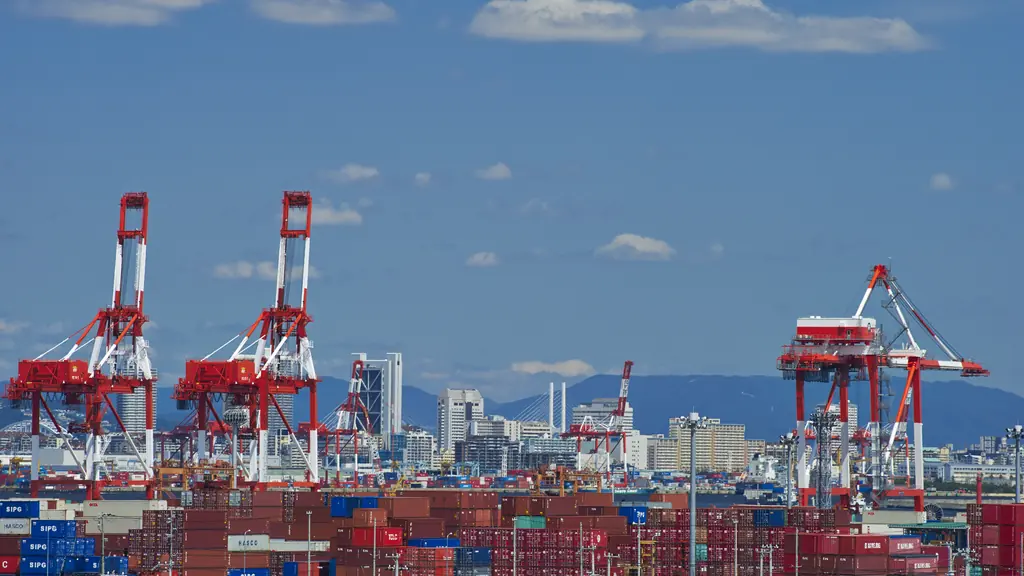 Ship-to-shore gantry cranes standing over a container yard at a deep-sea terminal.