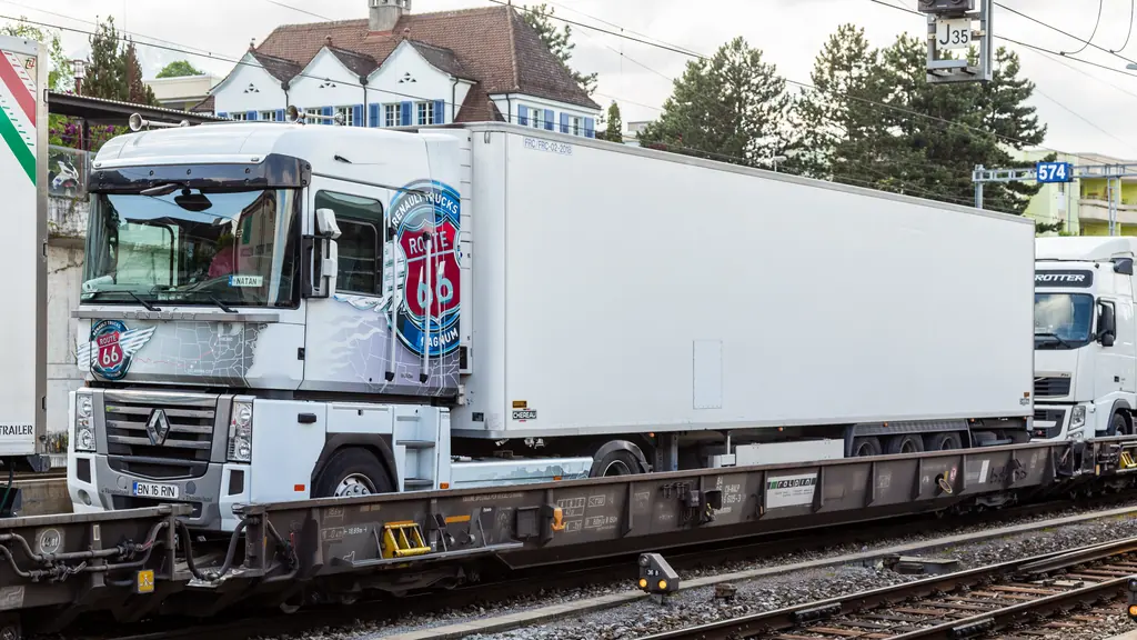 An articulated lorry loaded on a low railway wagon, waiting to be hauled through the Alps by train.